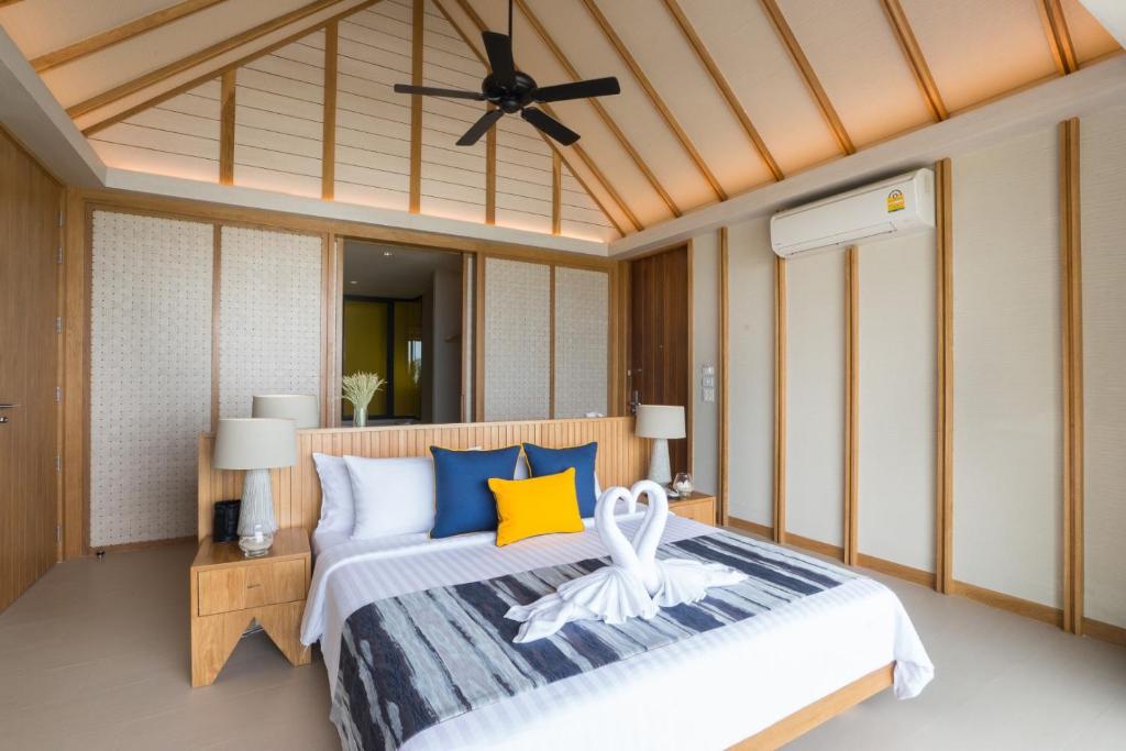 Mūsdienīgs guļamistabas interjers ar koka elementiem, gaišām krāsām un dekoratīvām gultas segām, radot relaksējošu atmosfēru. Guļamistabā ir gultas ar izsmalcinātu dekoru un elegantiem lampām.