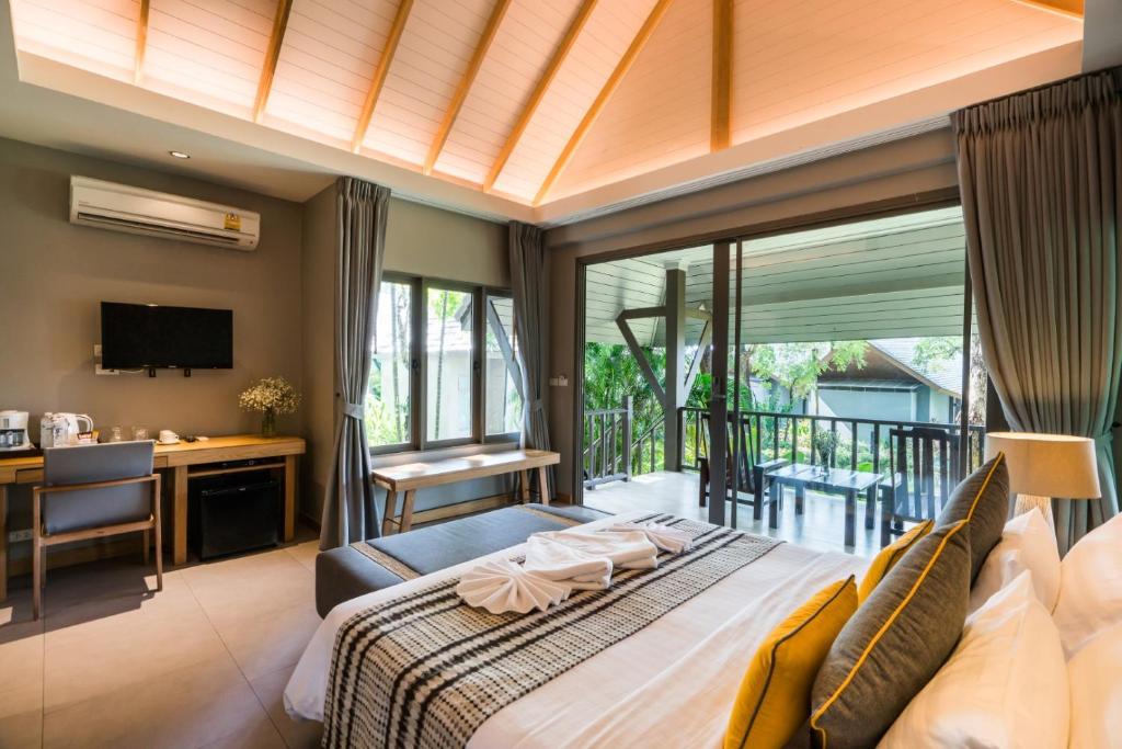 Mūsdienīga viesnīcas istaba ar gultu, darba galdu un terasi, kas sniedz skatu uz dārzu. Istabā ir televizors, gaisa kondicionētājs un omulīga atmosfēra.