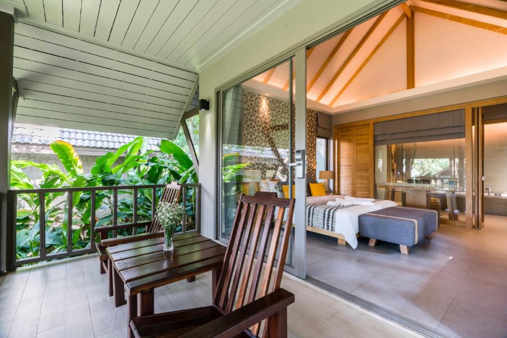 Mūsdienīga viesnīcas istaba ar plašu terasi, koka mēbelēm un zaļo dārzu fonā. Stilīgs interjers ar augstiem griestiem un dabīgām krāsām rada relaksējošu atmosfēru.