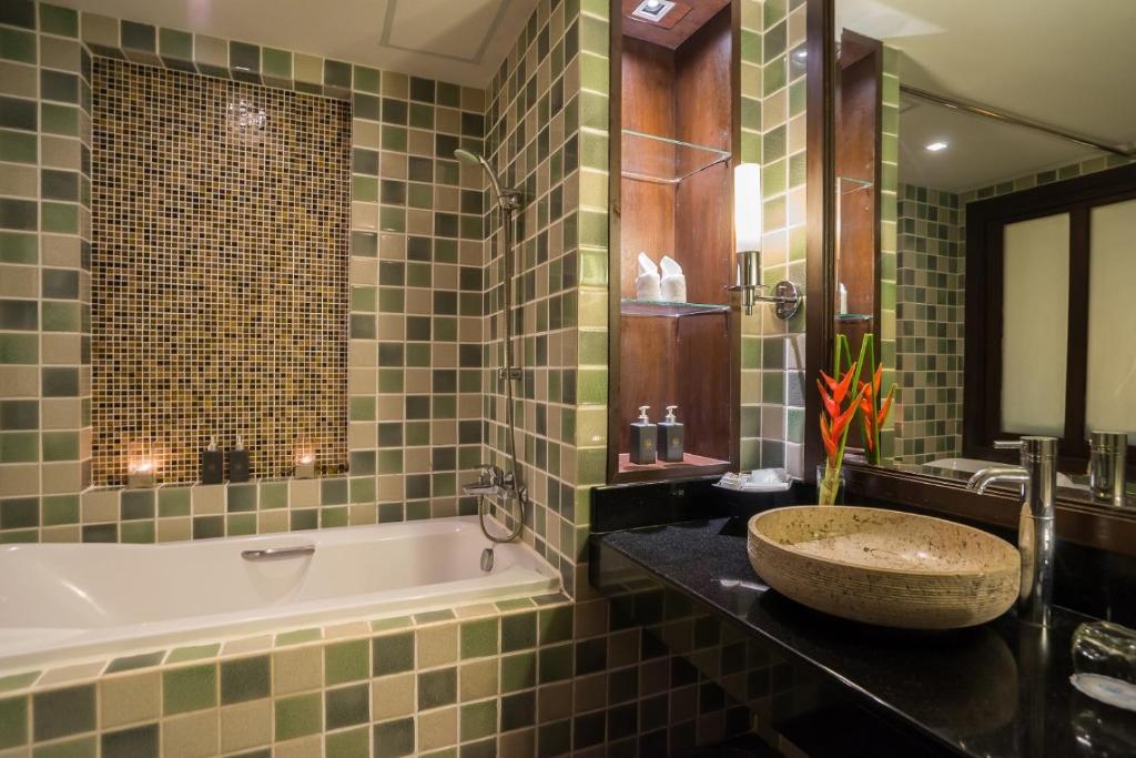 Moderns vannas istabas interjers ar flīzēm zaļā un brūnā tonī, vannu un elegantu izlietni. Papildināts ar dekoratīvām akcentiem un apgaismojumu.