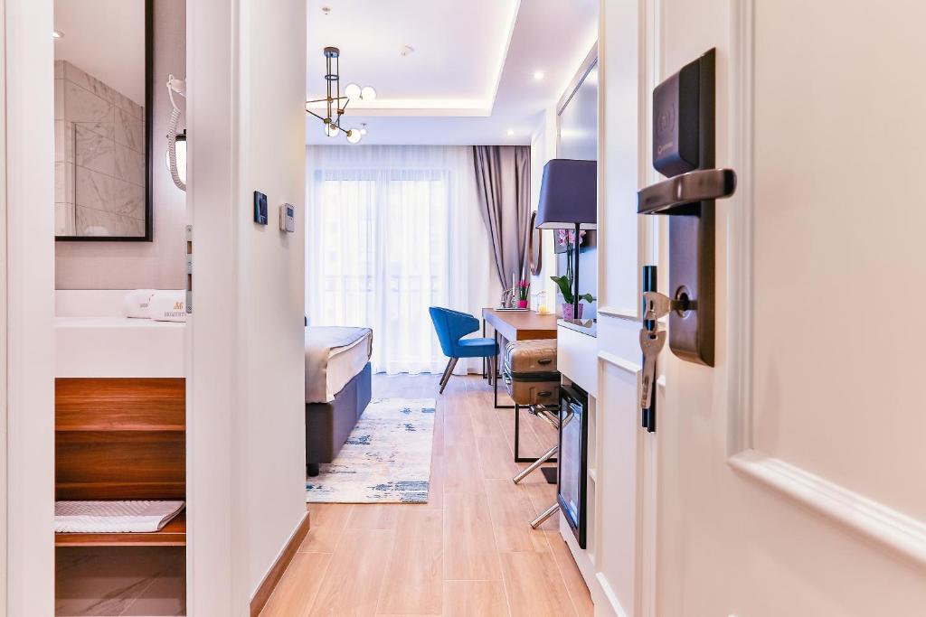 Mūsdienīgs viesnīcas numuriņš ar gaisīgu interjeru, kas iekļauj ērtu gultu, rakstāmgaldu un piekļuvi balkonam. Telpas apgaismojums un dekorācijas rada patīkamu atmosfēru.