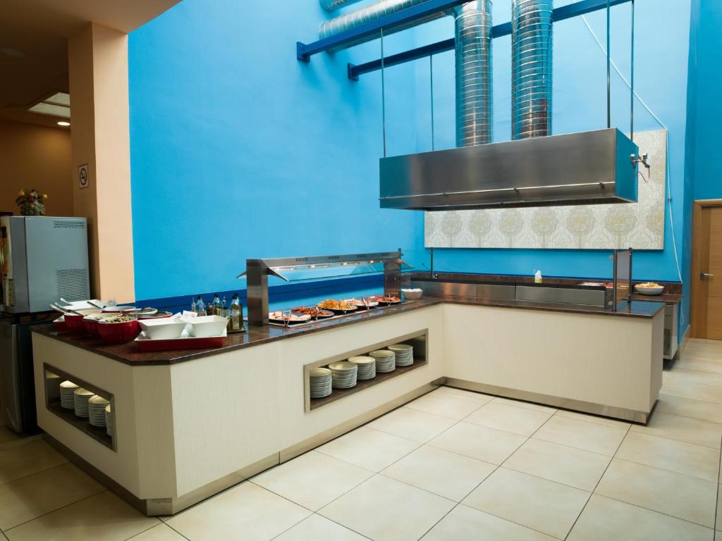 Mūsdienīga virtuve ar gaišām krāsām, ietilpīgu galdu un gatavām maltītēm. Plaša telpa ar zilu sienu un modernu aprīkojumu.