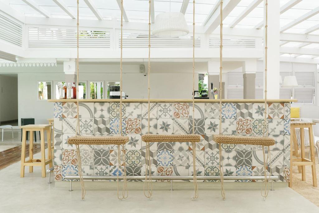 Mūsdienīgs bārs ar krāsainām flīzēm un šūpošanās krēsliem, kas apvieno stilu un komfortu. Gaisīga telpa ar daudz gaismas un atvērtu dizainu.