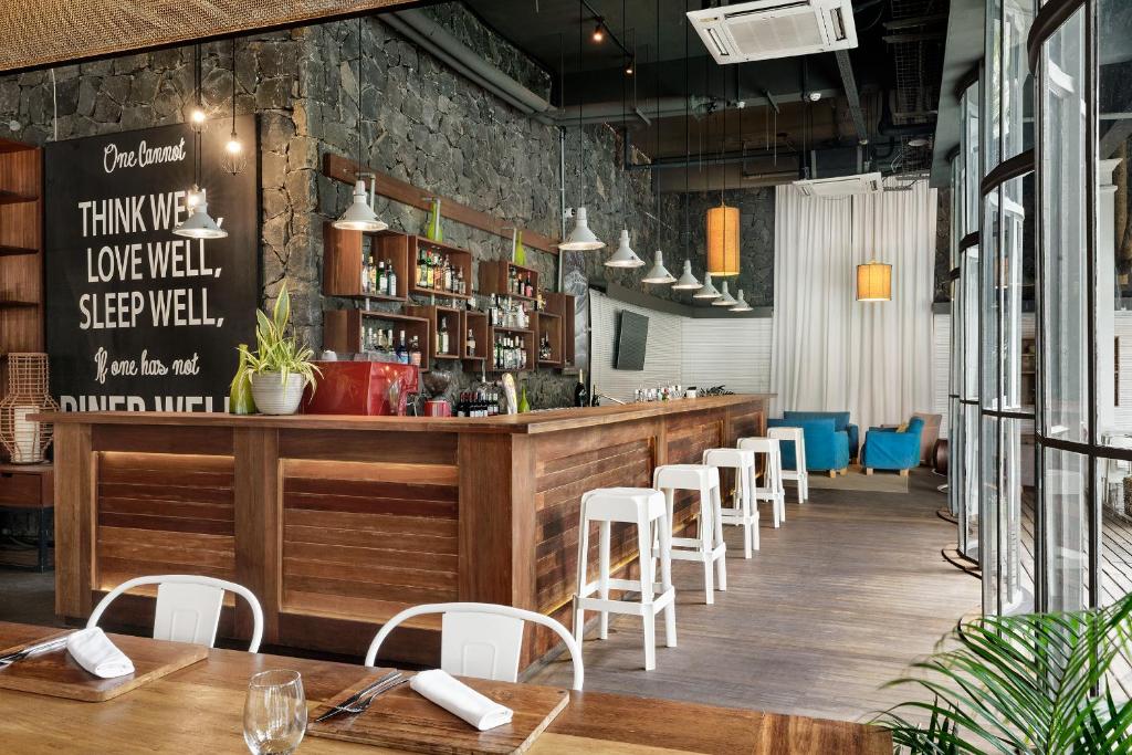 Mūsdienīgs bārs ar koka interjeru, kas piedāvā plašu dzērienu izvēli. Sienā izkārtoti plaukti ar alkoholiskajiem dzērieniem un izteiksmīga citāta izsistā plāksne.