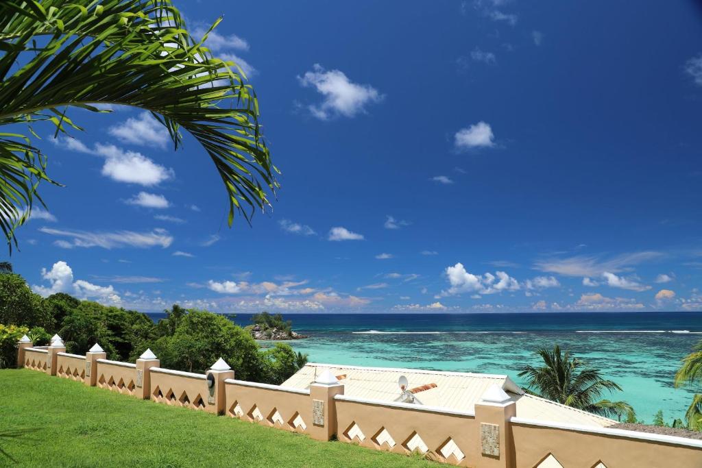Tropisks skats uz jūru un debesīm, ar zaļām palmu lapām priekšplānā un skaidru, zilo ūdeni. Ideāls atpūtas un brīvdienu galamērķis.