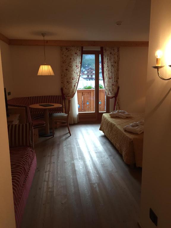 Mājīgs viesnīcas numurs ar koka grīdu, sarkanu svītrainu dīvānu un koka galdu, kā arī logu ar skatu uz kalniem. Interjers ir dekorēts ar ziedu aizkariem un siltu apgaismojumu.