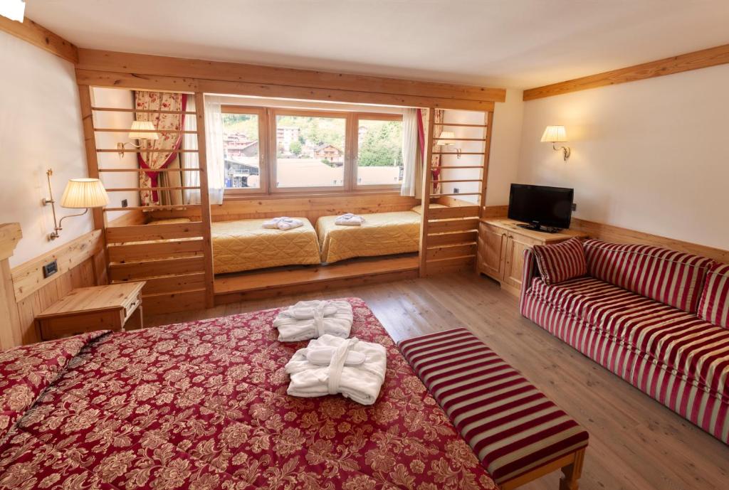 Skaista viesnīcas istaba ar koka apdari, divām gultām, dīvānu un televizoru. Lieli logi nodrošina dabīgu apgaismojumu un skatu uz apkārtni.