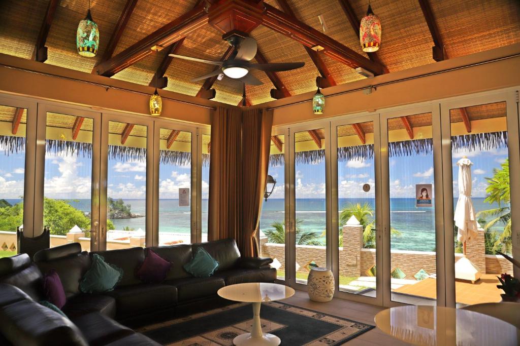 Labi iekārtota viesistaba ar panorāmas skatu uz jūru, kurā ir melna dīvāna komplekts, krāsainas lampas un lieli logi, kas atveras uz terasi.