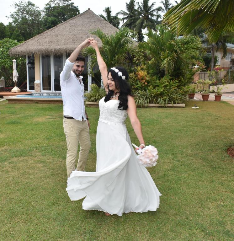 Jaunlaulātie pāri priecīgi dejo dārzā, apņemoties viens otru. Sieva valkā baltu kāzu kleitu ar puķu vainagu, bet vīrs ir ģērbies baltā kreklā un gaišās biksēs.