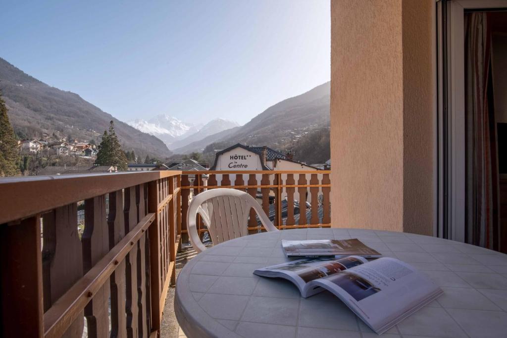 Balkona skats uz kalniem, kur pie galda atrodas grāmata un krēsls, radot mierīgu un relaksējošu atmosfēru.