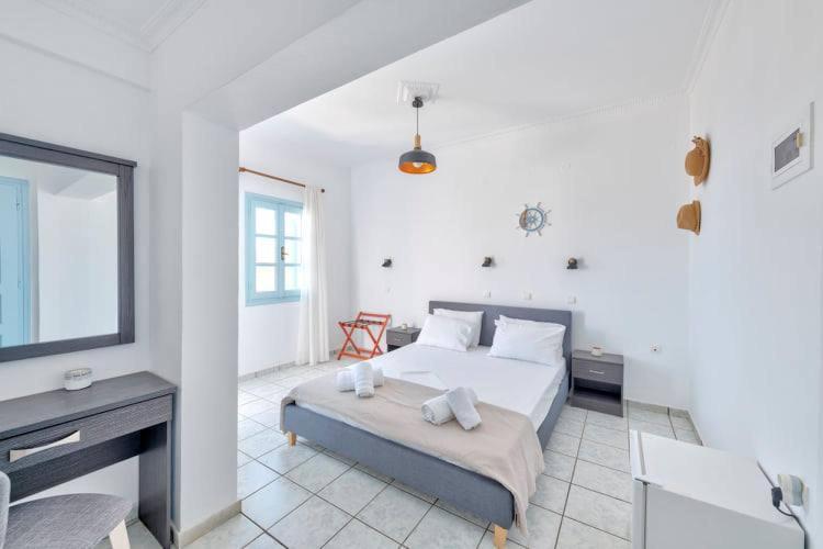 Gaiša viesnīcas istaba ar divguļamo gultu, galdu un spoguli, kas papildināta ar elegantiem dekoriem un logiem, kas ļauj ieplūst dabiskajai gaismai.