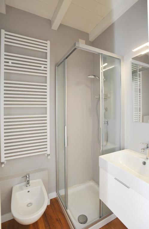 Mūsdienīgs vannas istabas interjers ar dušas kabīni, bidē un baltu izlietni. Izsmalcināts dizains ar siltuma radiatoru un gaismas spuldzēm.