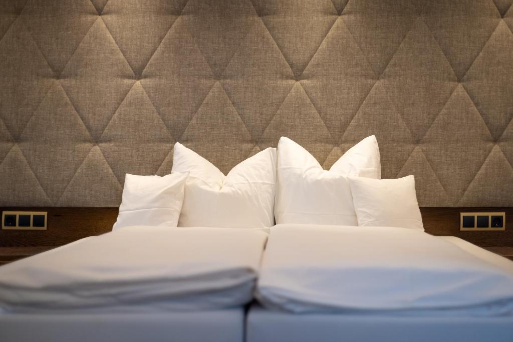 Mūsdienīga guļamistaba ar baltām spilveniem un elegantu, teksturētu sienu. Ideāla atmosfēra relaksācijai un komfortam.