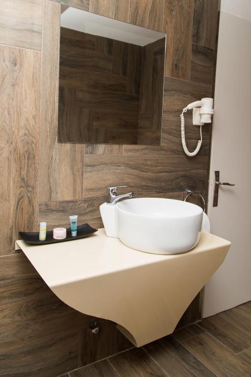 Moderns vannas istabas izkārtojums ar unikālu izlietni un koka apdari. Uz plaukta redzami krēmi un kosmētika.