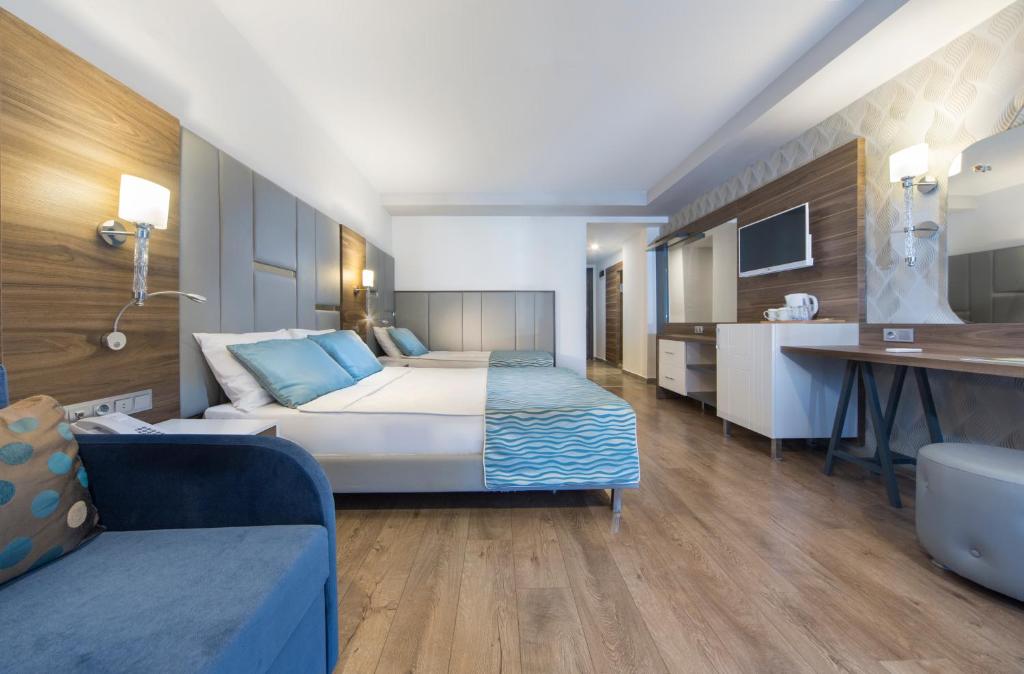 Mūsdienīga viesnīcas numura iekārtojums ar divām gultām, koka grīdu un elegantu mēbeļu dizainu. Telpā ir televizors, galds un atpūtas zona.