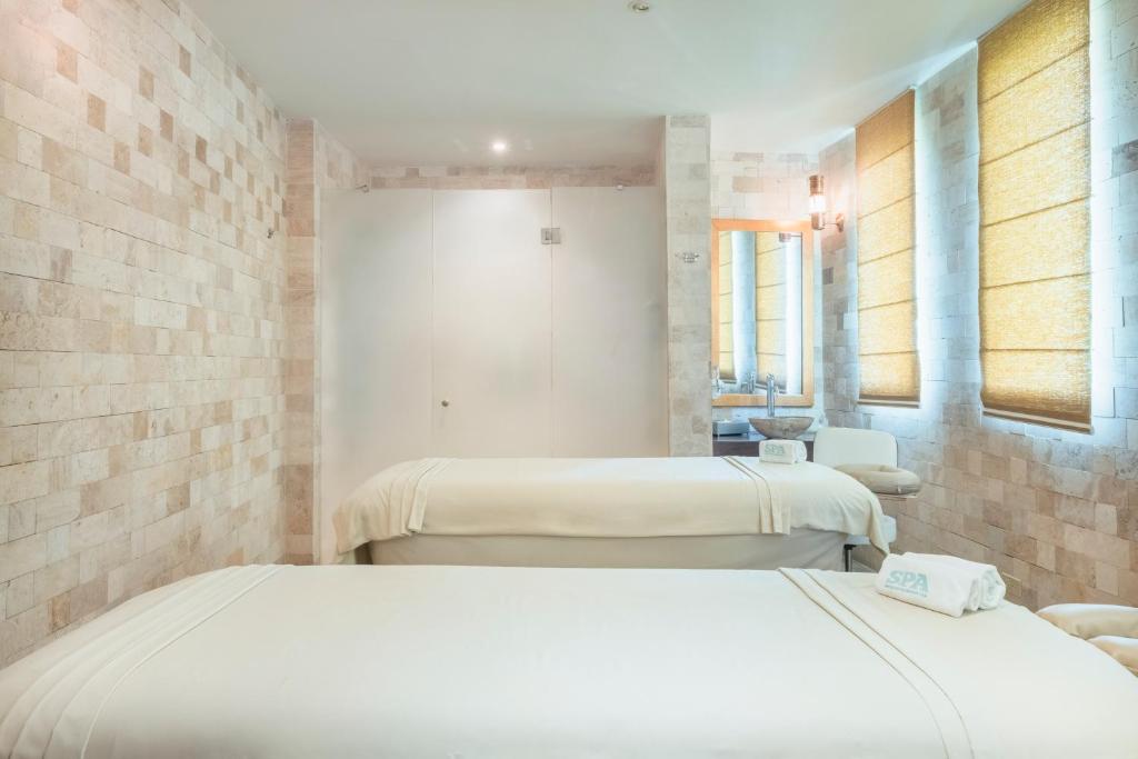 Mūsdienīgs spa telpa ar divām masāžas gultām un dabīgā akmens sienām, kas nodrošina relaksējošu atmosfēru. Logi ar žalūzijām ļauj kontrolēt gaismu un privātumu.