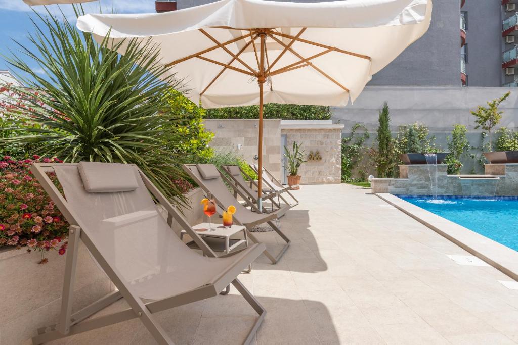 Peldbaseins ar saulessargiem un atpūtas krēsliem, apkārt ziedošas puķes un zaļumi, ideāli piemērots relaksācijai.