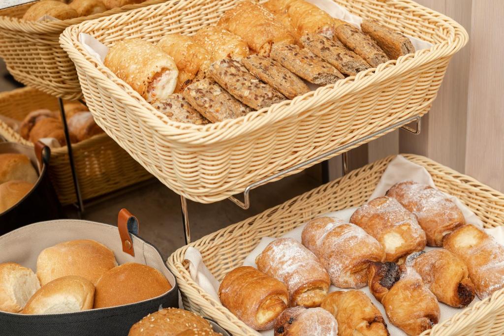 Maizes un konditorejas izstrādājumu grozs ar dažādiem ceptiem izstrādājumiem, tostarp maizītēm un cepumiem. Ievietots ratiņos, tas rada mājīgu un ērtu atmosfēru.