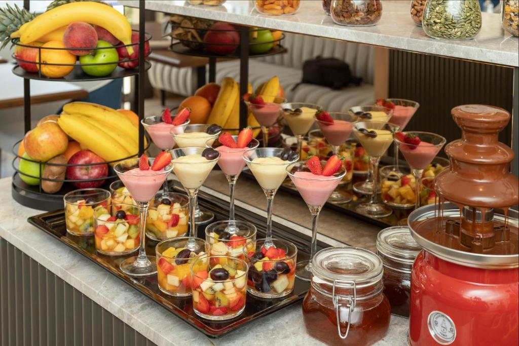 Krāsains deserts ar augļiem un saldējumu, kas pasniegts elegantā bufetē, kurā iekļauti augļi, deserts un šokolādes strūklaka.