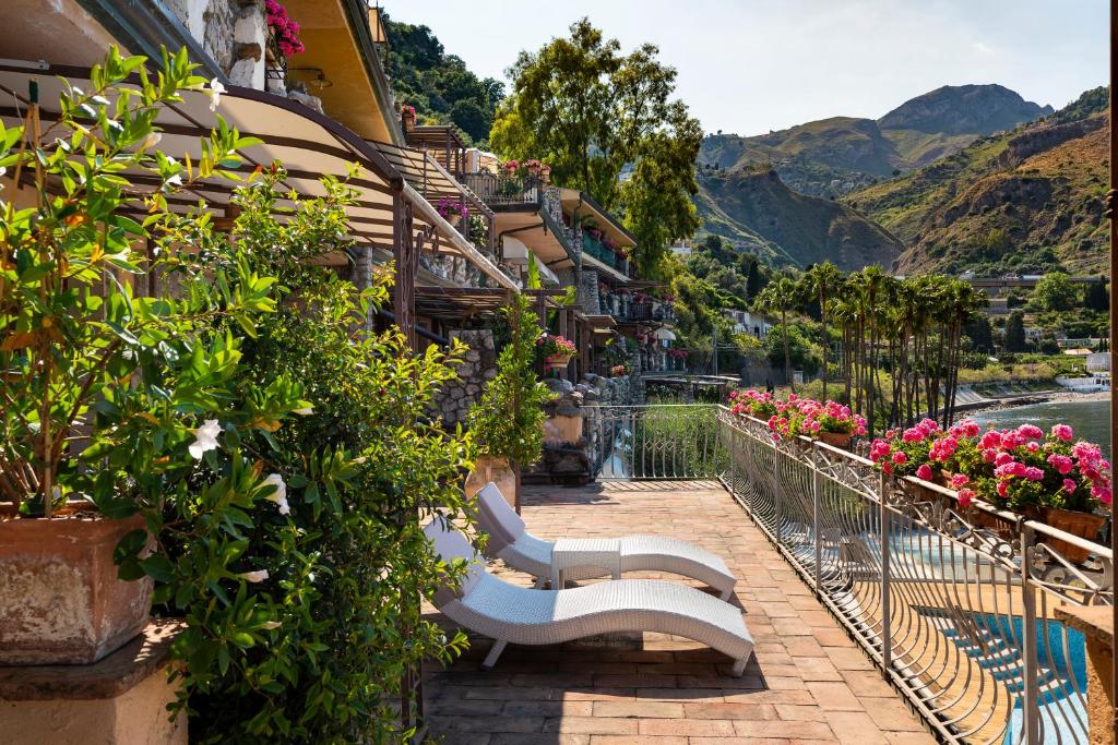 Saulaina terase ar sauļošanās krēsliem un ziedošiem augiem, skats uz kalniem un ūdeni, ideāla vieta atpūtai un relaksācijai.