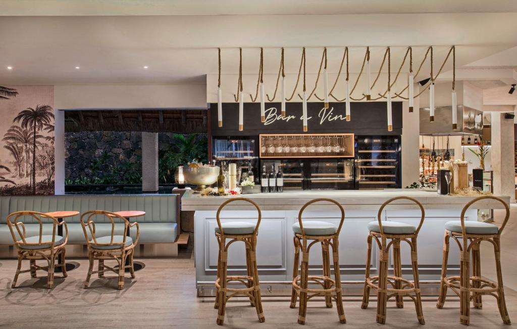 Moderns bārs ar stilu, kurā ir eleganti ratiņu krēsli un mūsdienīgs dizains, kas akcentē ciedru un zaļumu. Ideāla vide atpūtai un dzērienu baudīšanai.