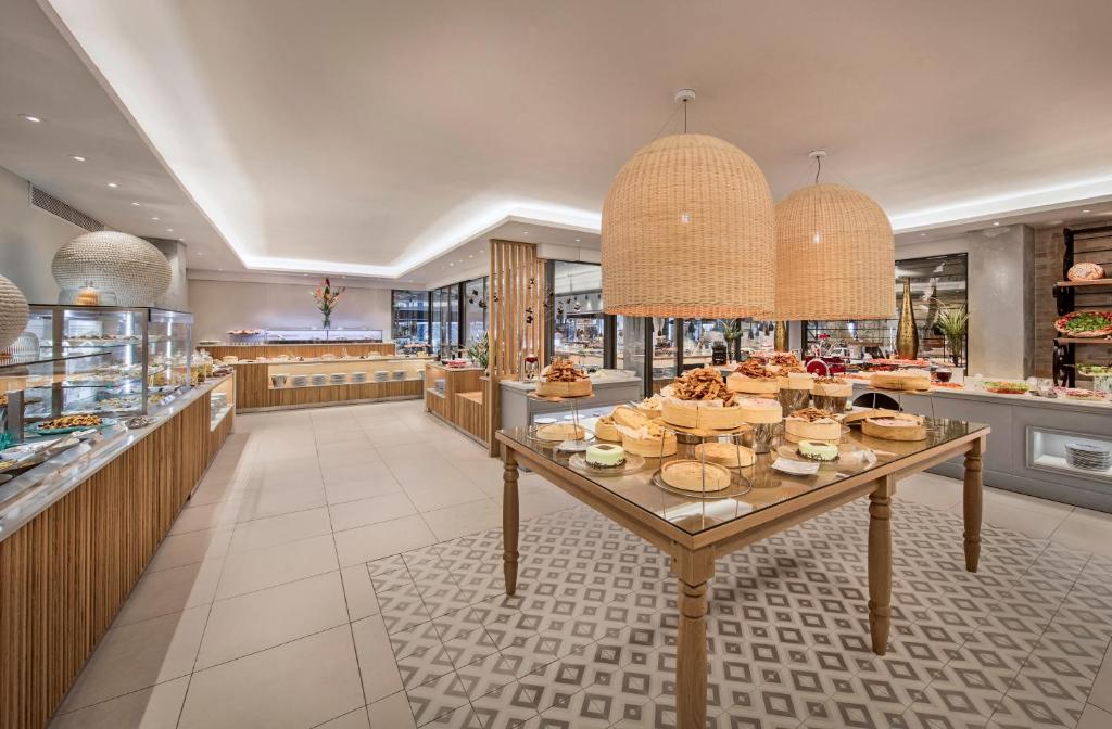 Mūsdienīga bufete ar plašu pārtikas izvēli, ieskaitot saldumus un uzkodas, apgaismota ar vītņu lampām un modernu interjeru.