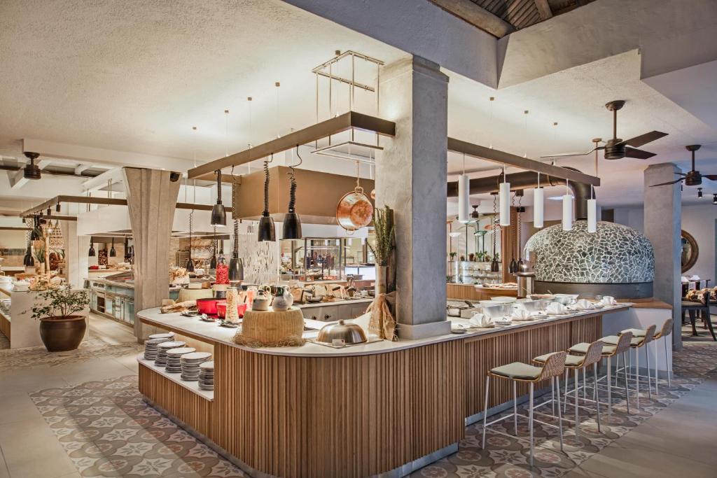 Moderns restorāns ar atvērtu virtuvi, kas piedāvā plašu ēdienu klāstu un stilīgu interjeru, apvienojot koka un akmens elementus. Gaismas un ventilatori rada patīkamu atmosfēru.