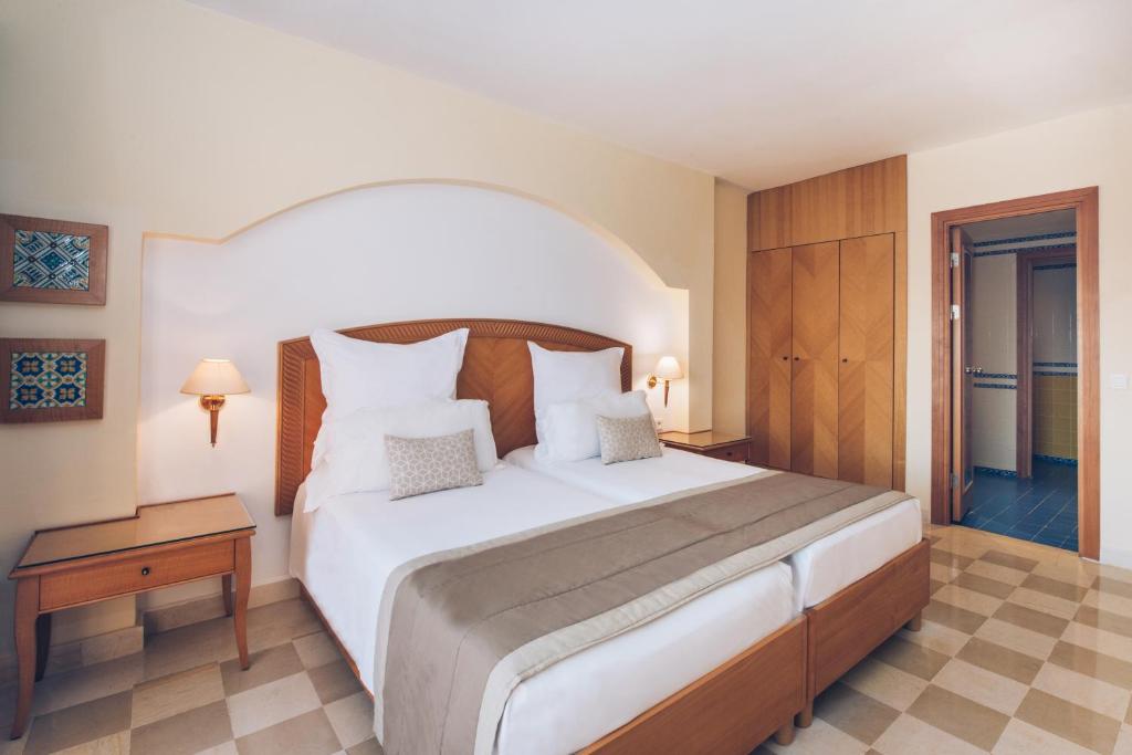 Mūsdienīga viesnīcas numura interjers ar divām gultām, koka mēbelēm un siltu apgaismojumu. Sienās ir dekoratīvi mākslas darbi, kas piešķir telpai patīkamu atmosfēru.