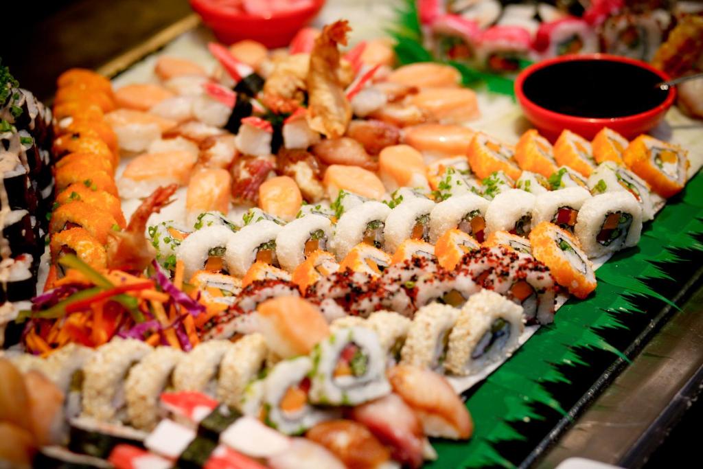Svaigu sushi un sīkiņi, kas sakārtoti krāšņā kompozīcijā, papildināti ar sojas mērci un dārzeņu rotājumiem. Ideāls izvēle japāņu virtuves mīļotājiem.