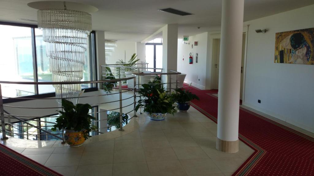 Gaismas un moderns koridors ar spirālveida lustru, zaļām augiem un mākslas darbiem uz sienām, piedāvājot elegantu atmosfēru.