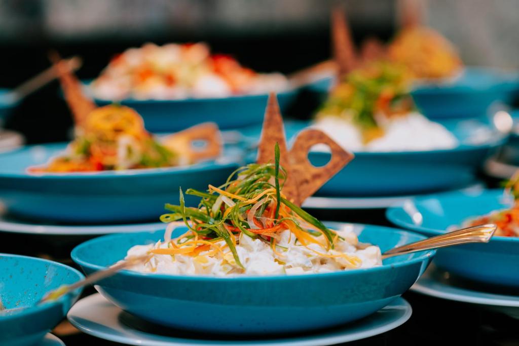 Skaisti zili trauki ar rīsu ēdieniem, dekorēti ar dārzeņiem un kraukšķīgiem elementiem. Ideāli piemēroti svinībām vai svinīgām maltītēm.