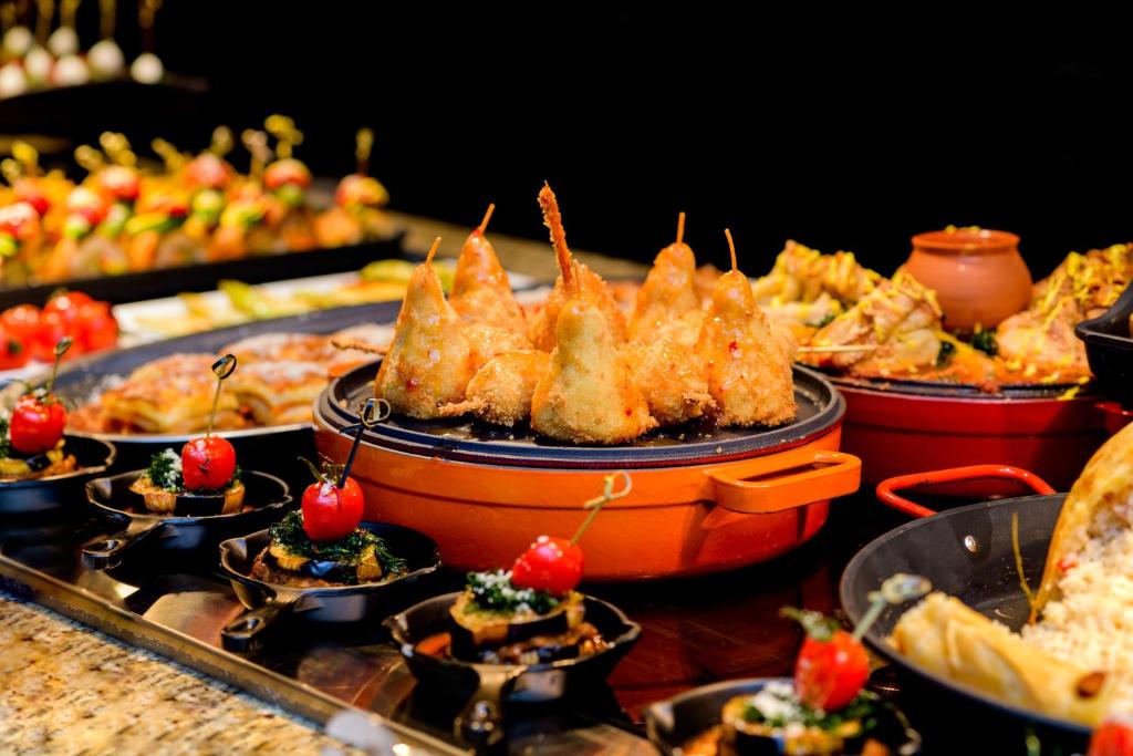 Bagātīgs ēdienu klāsts ar kraukšķīgām uzkodām un sulīgiem dārzeņiem, izkārtots elegantā bufetē. Erotiskā krāsu kombinācija un pievilcīgi pasniegti ēdieni rada svinīgu atmosfēru.