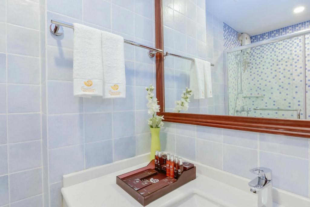 Moderns vannas istabas interjers ar baltām dvieļiem, higiēnas produktiem un ziediem, radot svaigu un elegantu atmosfēru.