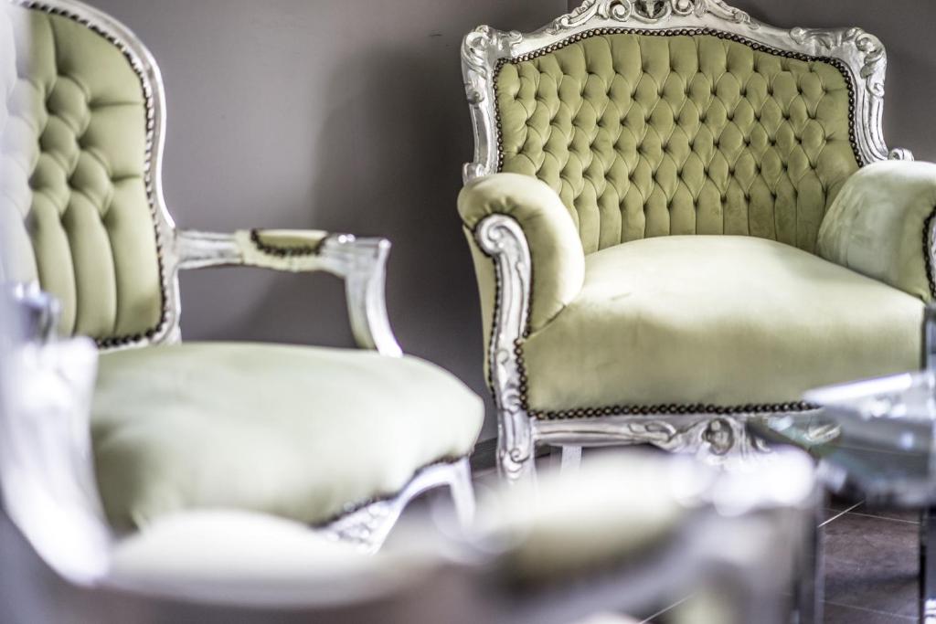 Eleganti zaļi krēsli ar greznu apdari un izsmalcinātu dizainu, kas piešķir istabai greznību un stilu.