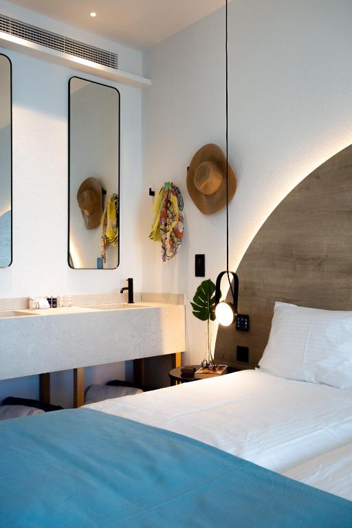 Mūsdienīgs guļamistabas interjers ar diviem spoguliem, stilīgu izlietni un gultu ar zilu gultas veļu. Telpā ir piekārti aksesuāri, piemēram, cepure un šalle, radot mājīgu atmosfēru.