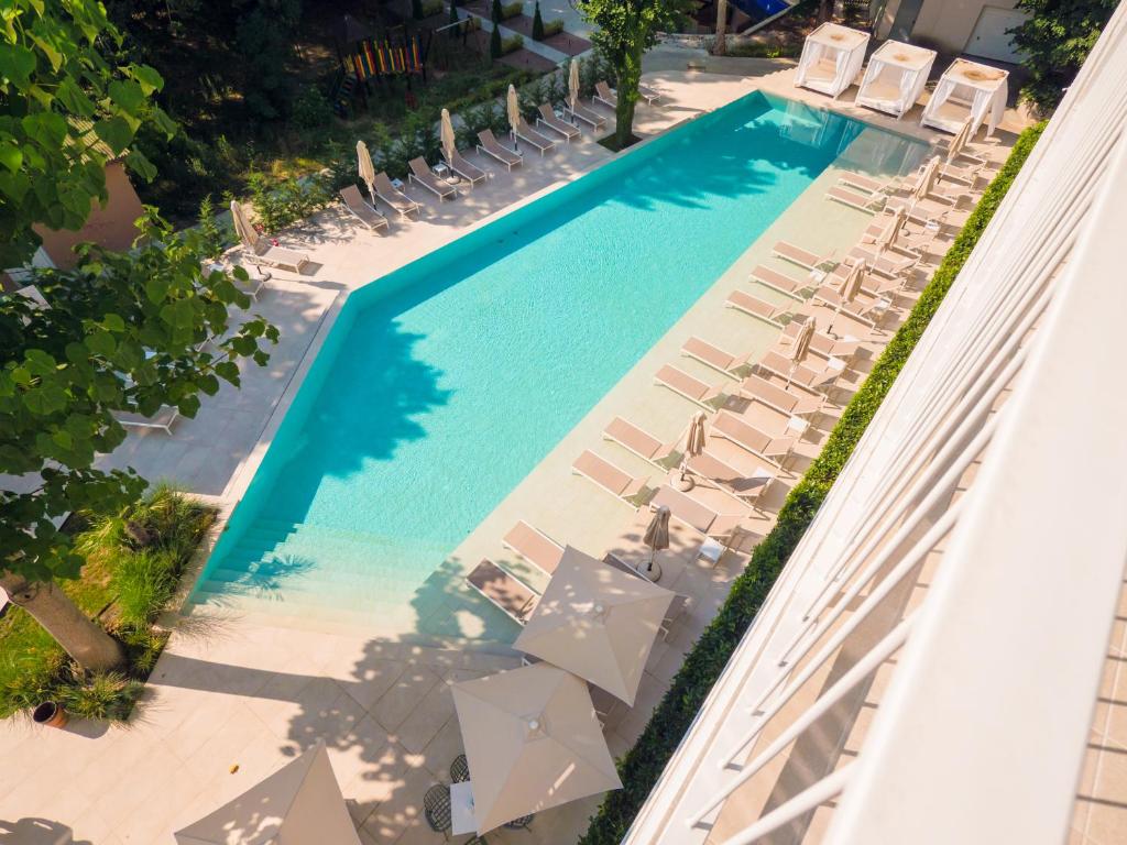 Peldbaseins ar sauļošanās krēsliem un saulessargiem, apkārt zaļojošiem kokiem un ainavām. Ideāla vieta atpūtai un relaksācijai.