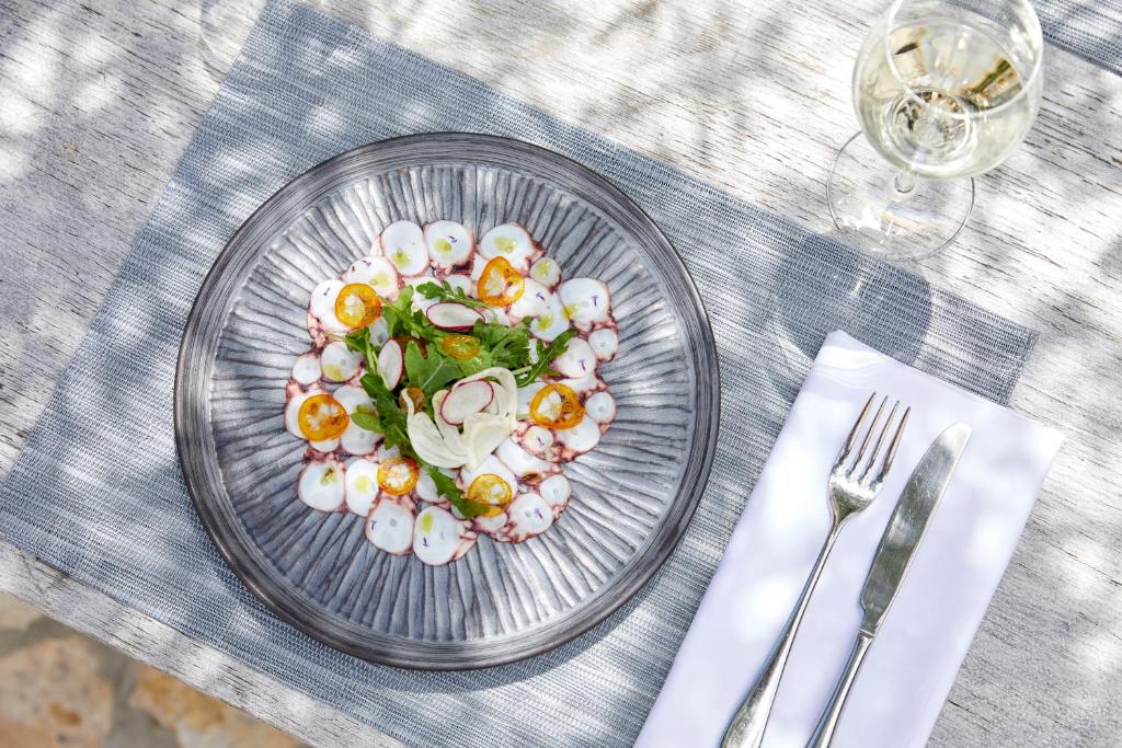 Svaiga jūras veltes, kas pasniegtas uz eleganta šķīvja ar dārzeņiem un garšaugiem, kopā ar glāzi vīna. Ideāla maltīte vasaras dienai.