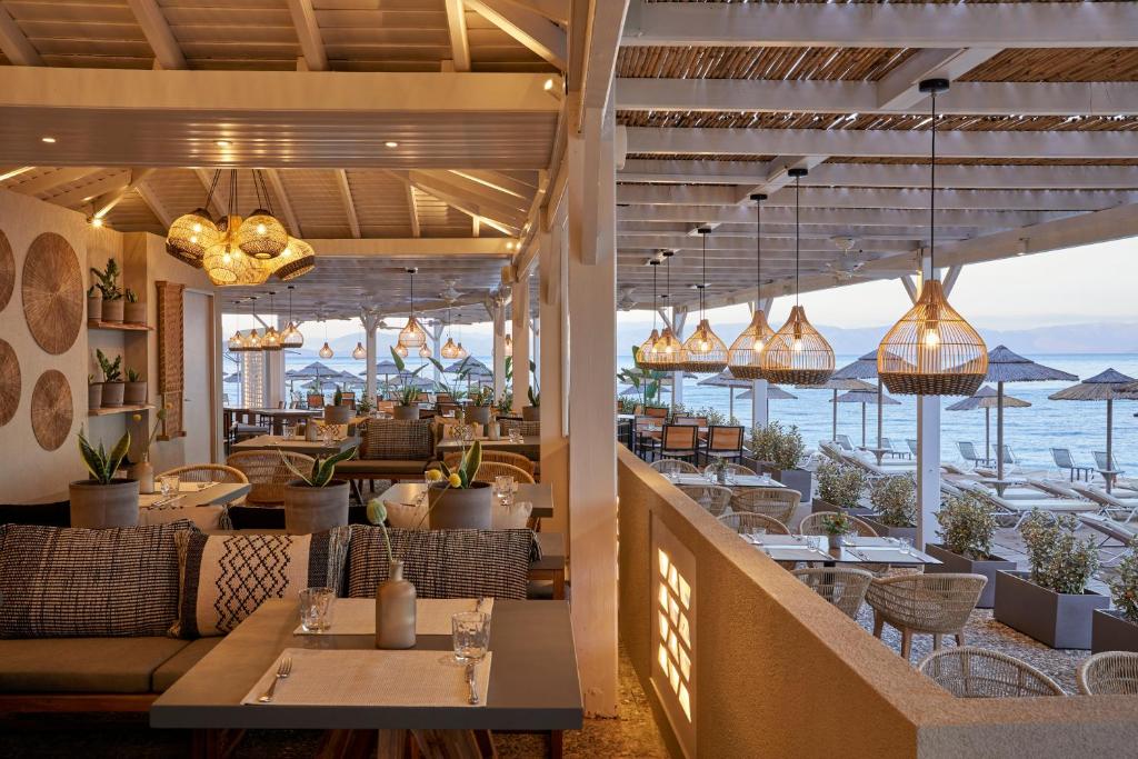 Mūsdienīgs restorāns ar jūras skatu, elegantiem interjera elementiem un gaišām lampām, nodrošina patīkamu atmosfēru. Terase ar sauļošanās krēsliem un lietussargiem papildina relaksējošo vidi.