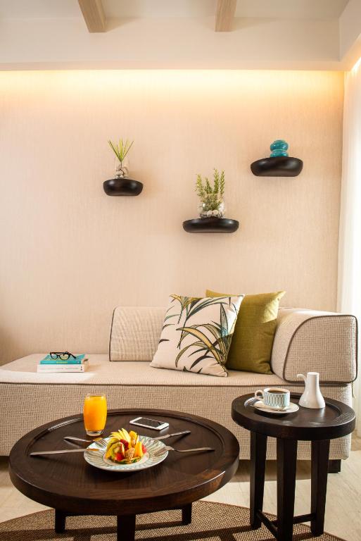 Mūsdienīgs viesistabas interjers ar dīvānu, galdiem un dekoratīvām augiem uz sienas. Uz galda redzama augļu porcija un dzēriens.
