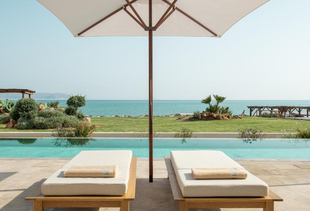 Atpūtas vieta ar divām sauļošanās gultām un saules jumtu pie baseina, ar skatu uz jūru un dārzu. Ideāla vieta relaksācijai un atpūtai.