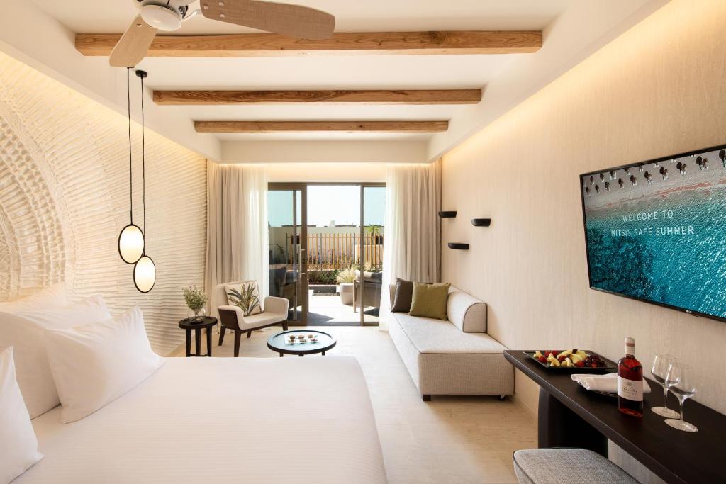 Mūsdienīga viesnīcas numura iekšskats ar koka griestiem, gaišām sienām un plašu balkonu. Numurā ir ērtas mēbeles, televizors un dekoratīvi elementi.