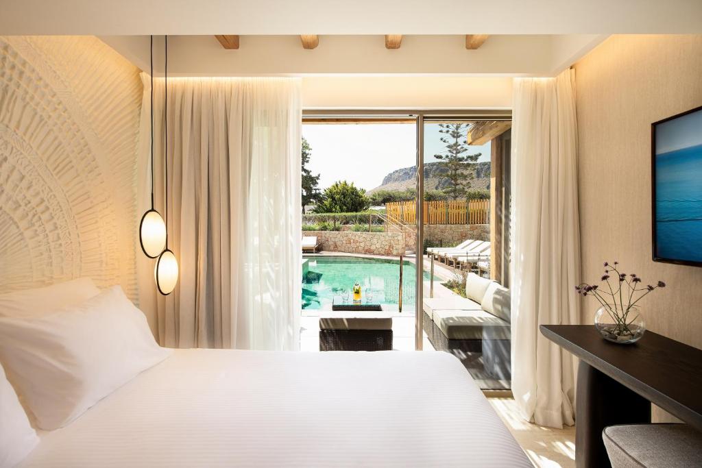 Moderns viesnīcas numurs ar gaisīgu interjeru, skatu uz peldbaseinu un dārzu. Telpā ir gulta, rakstāmgalds un lieli logi, kas ielaiž dabisko apgaismojumu.