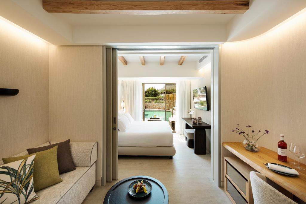 Mūsdienīga viesnīcas numura interjers ar viesistabu, guļamistabu un skatu uz dārzu. Telpā ir dabiski toņi, eleganta mēbeles un ērti sēdvietas, kas rada relaksējošu atmosfēru.