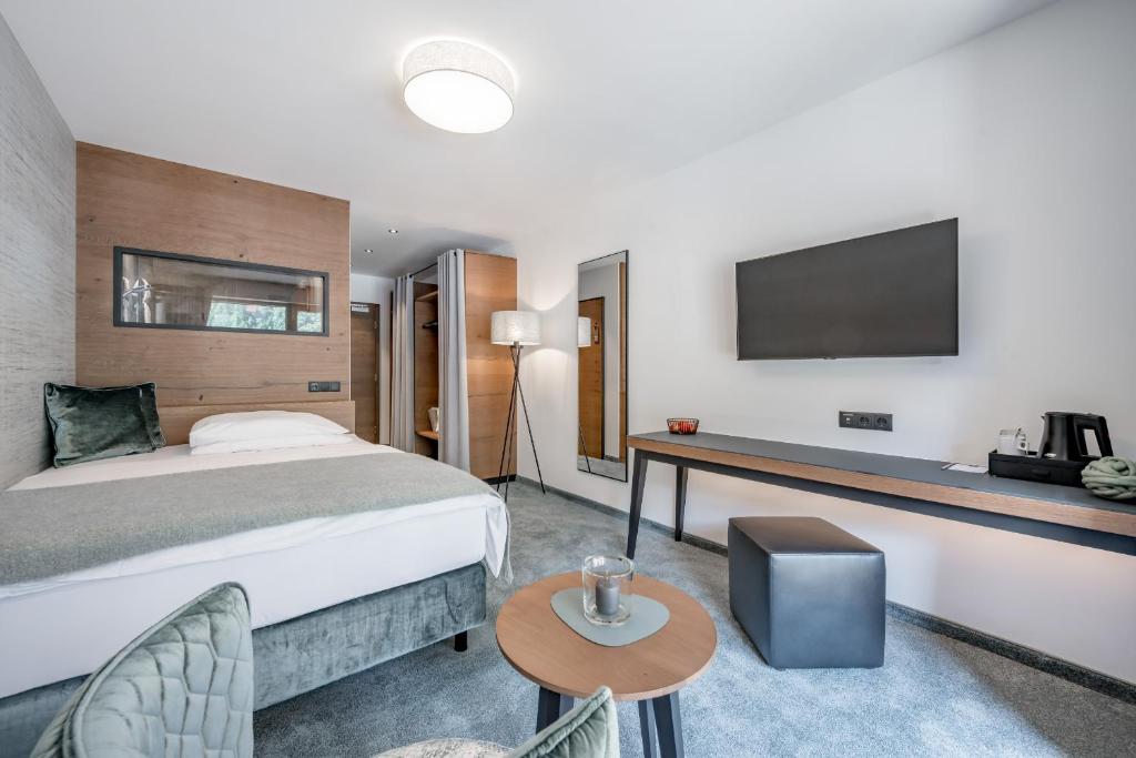 Mūsdienīga viesnīcas numuriņa interjers ar ērtu gultu, televizoru un galdu, kas nodrošina komfortablu atpūtu. Numuriņā ir arī skapji un apgaismojums.