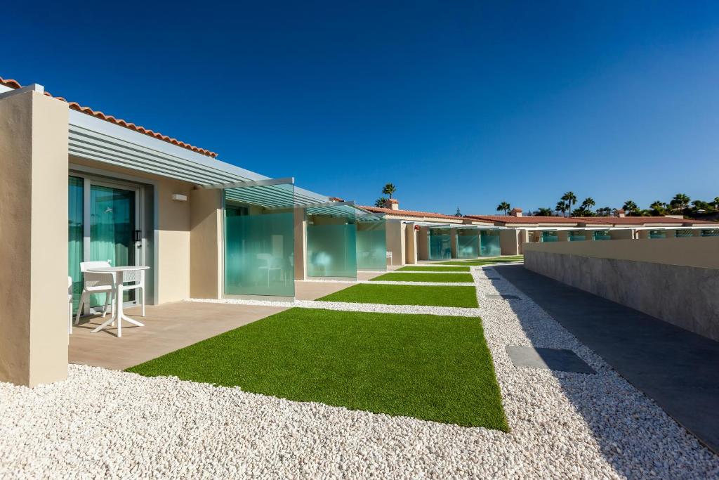 Mūsdienīga viesnīcas teritorija ar zaļajiem zālieniem un stikla balkoniem, kas atrodas saulainā dienā.