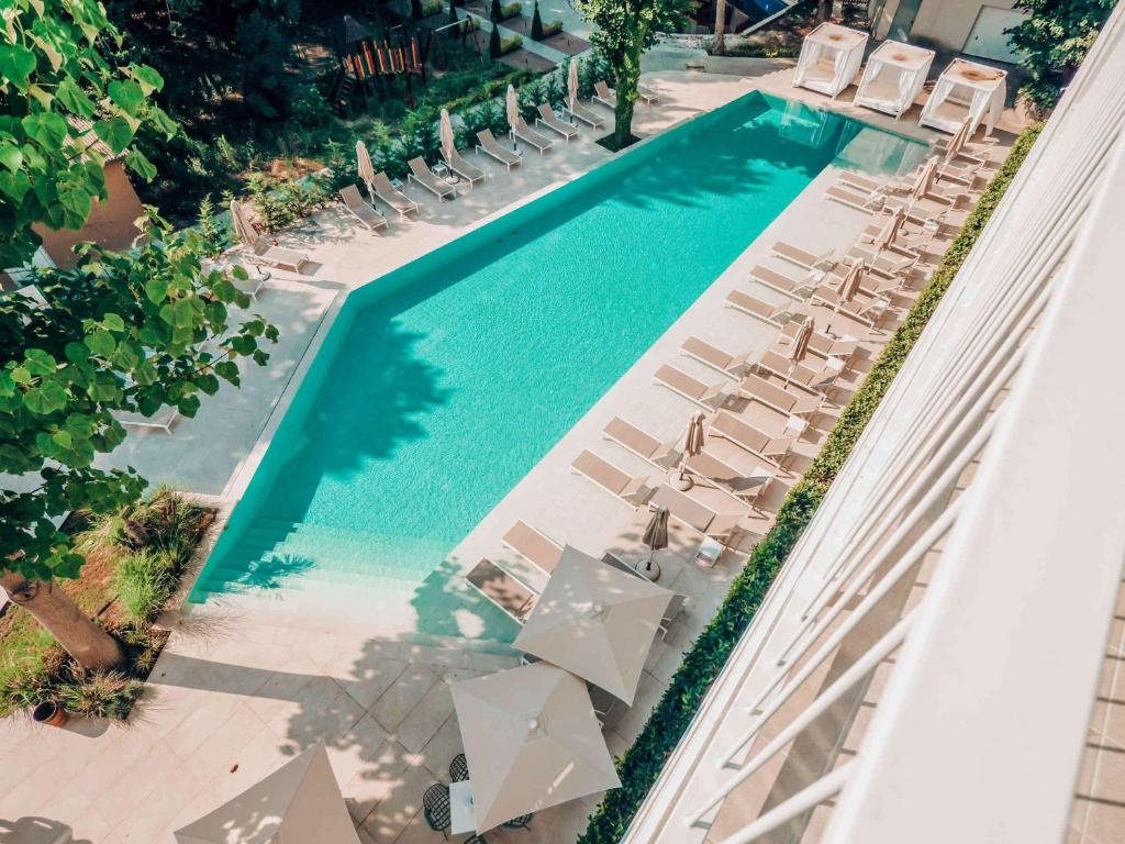 Peldbaseins ar saulessargiem un atpūtas krēsliem, ieskauts zaļiem kokiem un augu stādījumiem. Ideāla vieta relaksācijai un atpūtai.