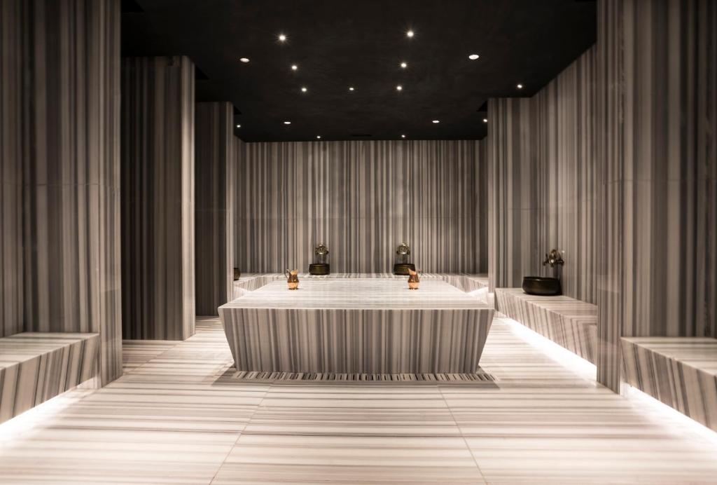 Mūsdienīgs spa interjers ar vertikāliem svītrains marmora paneļiem un minimālu apgaismojumu, radot relaksējošu atmosfēru. Elegants dizains ar funkcionālām nišām un vannu.