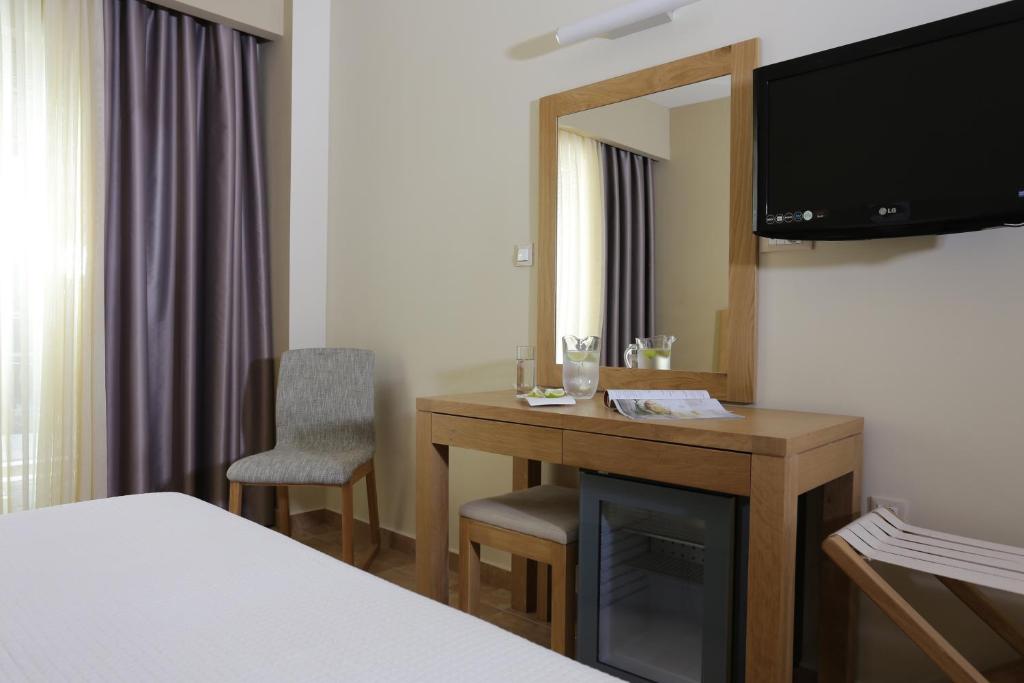 Mūsdienīgs viesnīcas numurs ar koka mēbelēm, televizoru un gaismas caurlaidīgu aizkaru. Uz galda ir ūdens karafe un neliels uzkodu šķīvis, blakus atrodas krēsls un saliekamā krēsla stūrī.