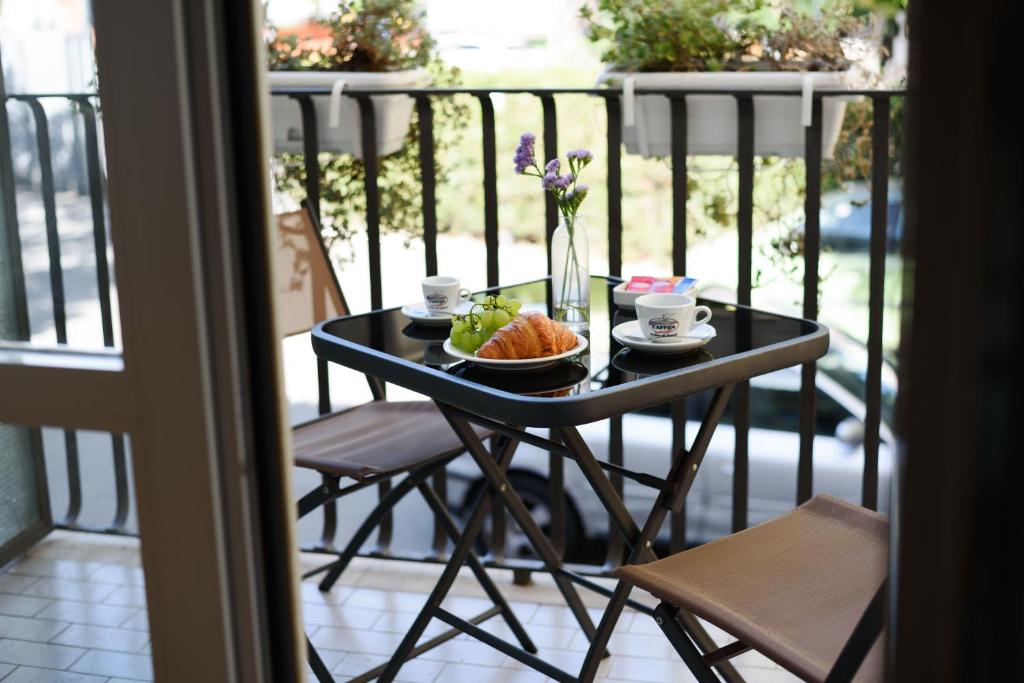 Svaiga brokastu galda kompozīcija uz balkona ar kruasānu, augļiem un kafiju, radot relaksējošu atmosfēru.