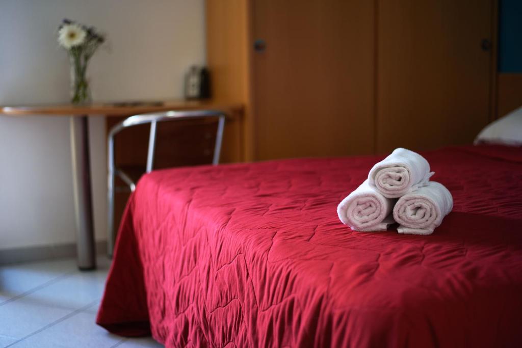 Sarkana gulta ar sakrāmētām baltām dvieļiem un dekoratīvu ziedu pušķi uz galda.